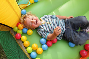 2 year old boy smiling on an inflatable bouncy castle
